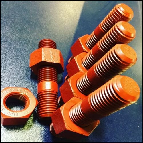20E Group of orange hex bolts with a matching nut on a blue surface, close-up of threaded shafts.